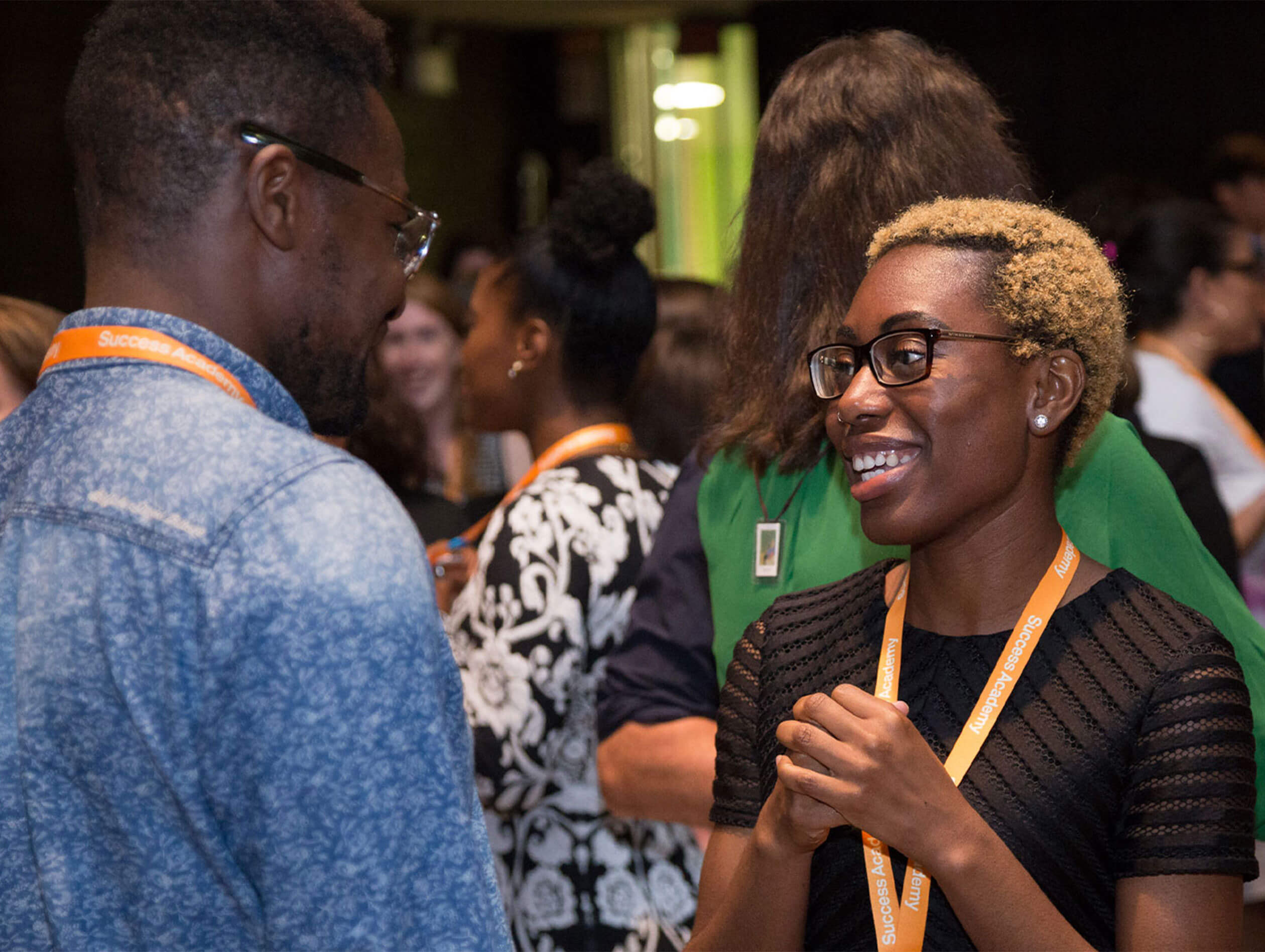 People talking at an event, wearing orange lanyards.
