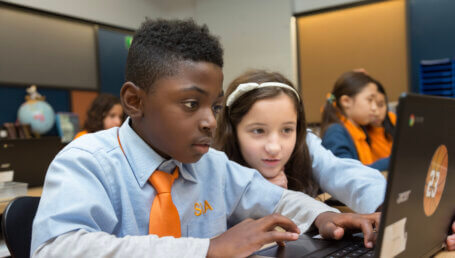 Two children in Success Academy uniforms looking at a laptop
