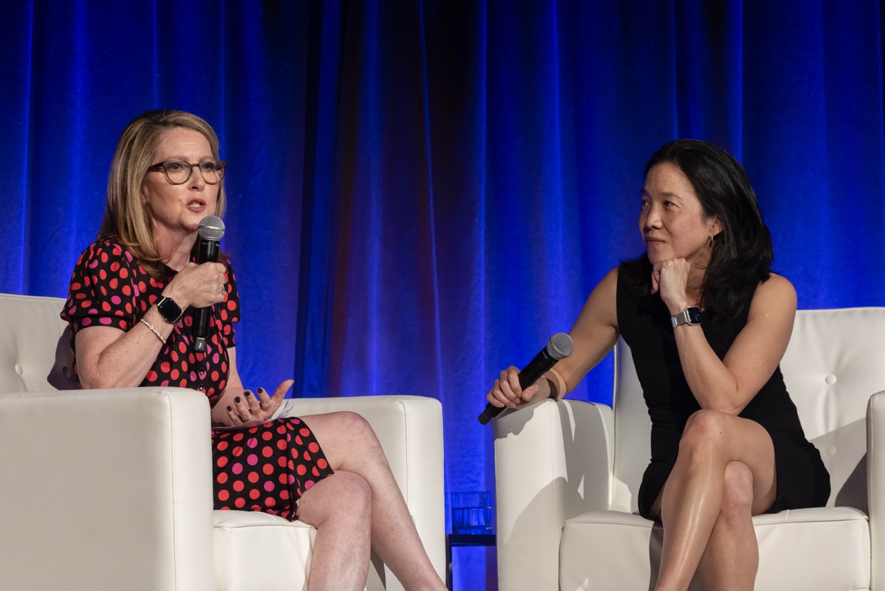 Success Academy Founder & CEO Eva Moskowitz and Dr. Angela Duckworth, New York Times best-selling author, hold microphones, seated on stage, conversing.