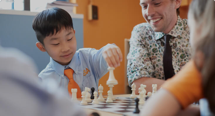 Student playing chess, guided by an instructor