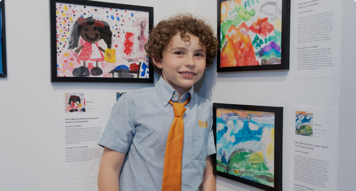 Young student in front of an art display showcasing their artwork