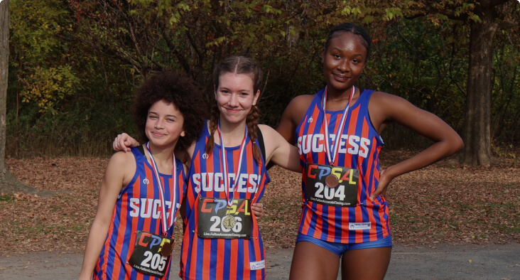 Three students wearing athletic gear after a cross-country event