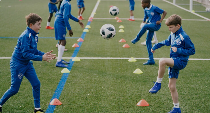 Young students practicing soccer on a field with cones