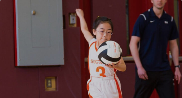Student practicing volleyball in a gymnasium