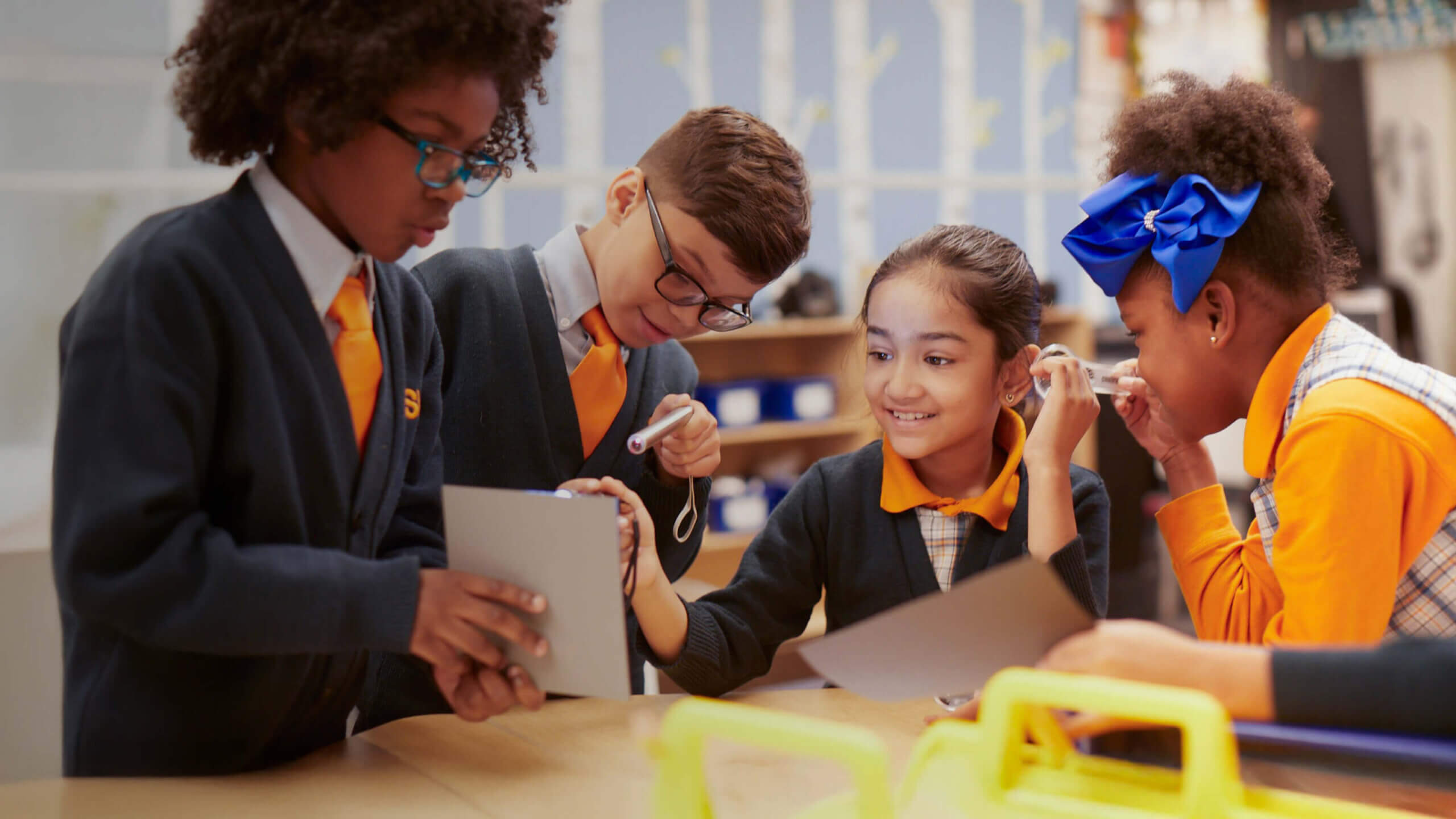 A group of four students gathered around a table looking at a science experiment.