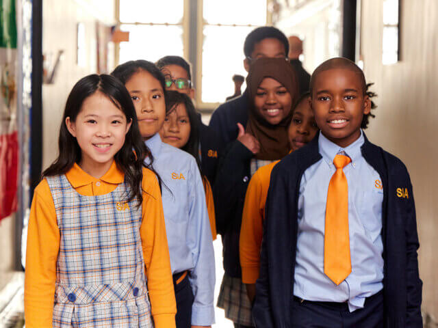 A group of children in school uniforms standing together in a hallway
