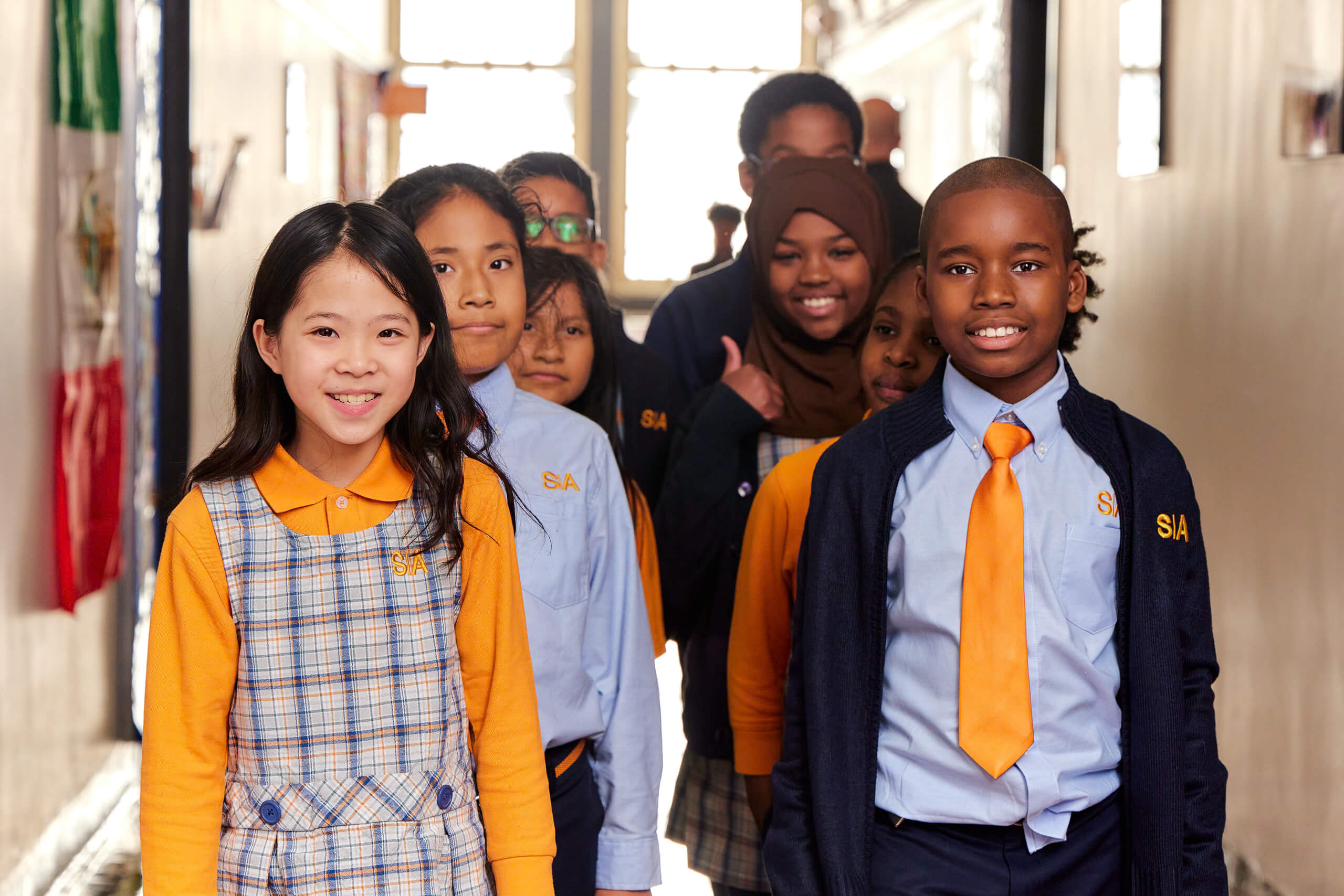 A group of children in school uniforms standing together in a hallway